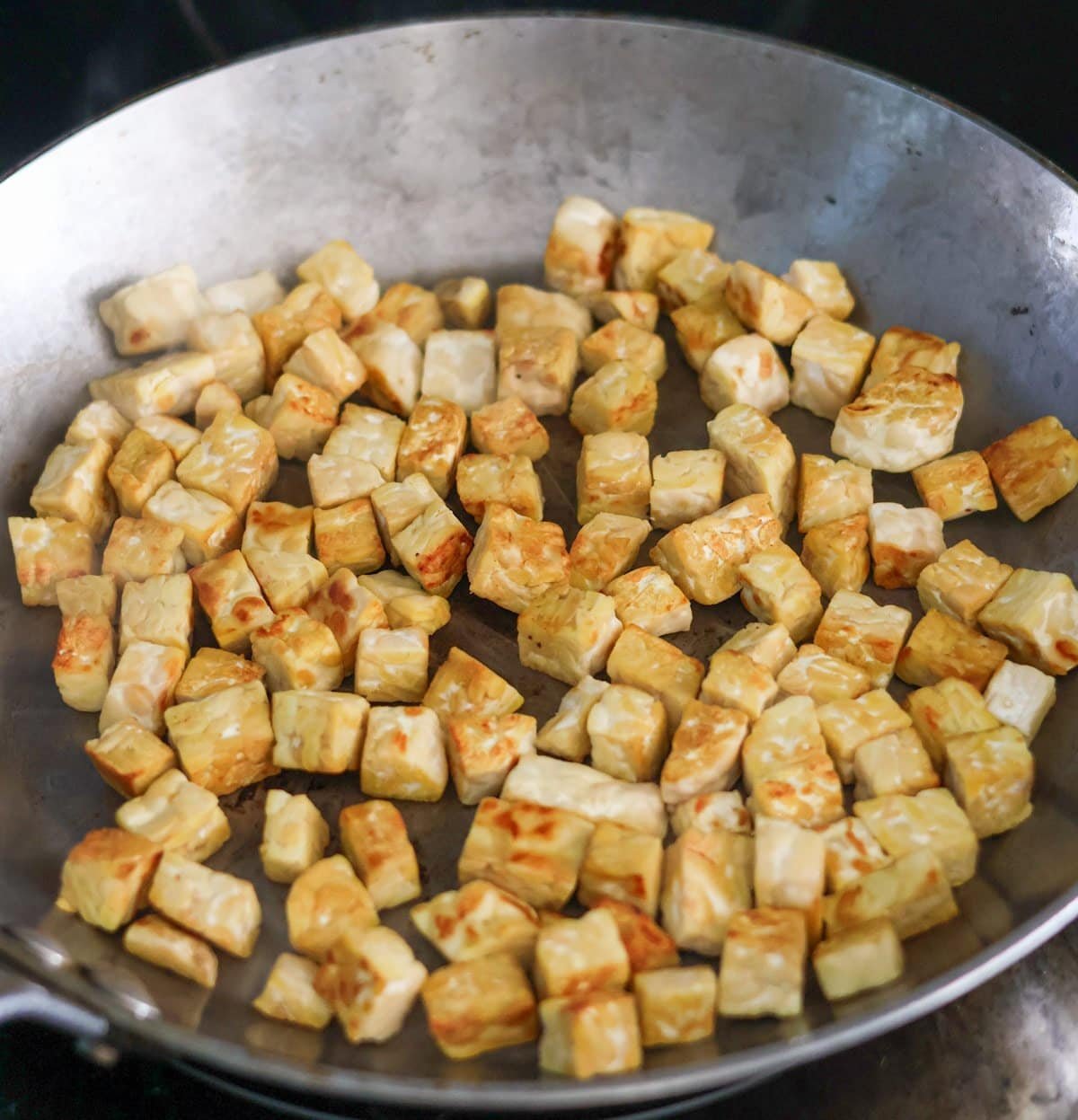 Fried tempeh in a cast iron pan.