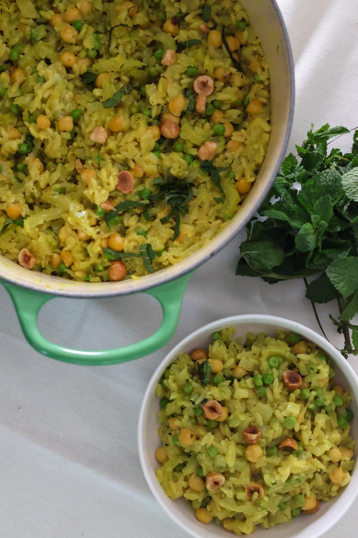 The orzo with chickpeas recipe in a large green pot and in a small white bowl on the side.