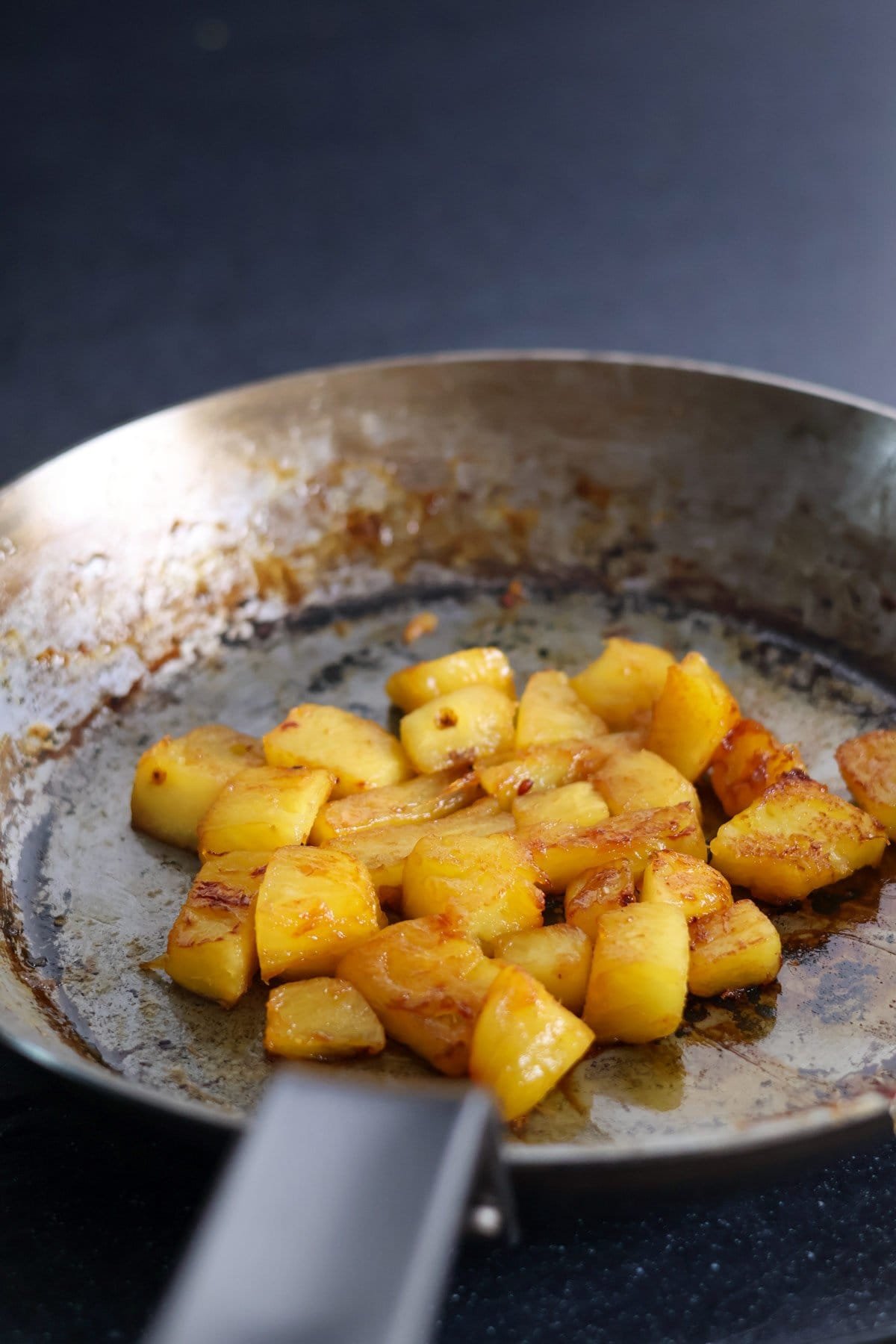 Caramelized pineapple pieces in a frying pan.