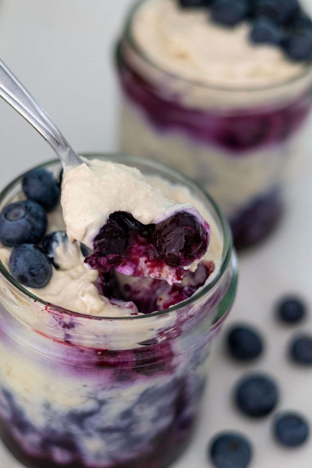 A spoonful of blueberry cheesecake overnight oats above a small mason jar.