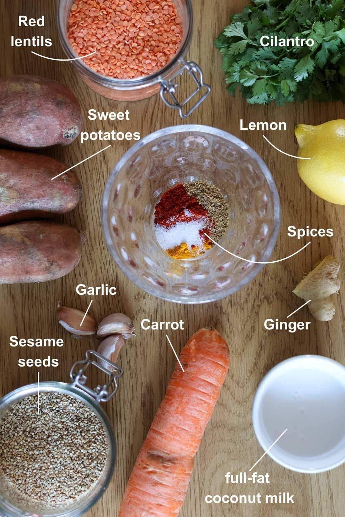 All the ingredients for the carrot sweet potato and ginger soup on a wooden table.