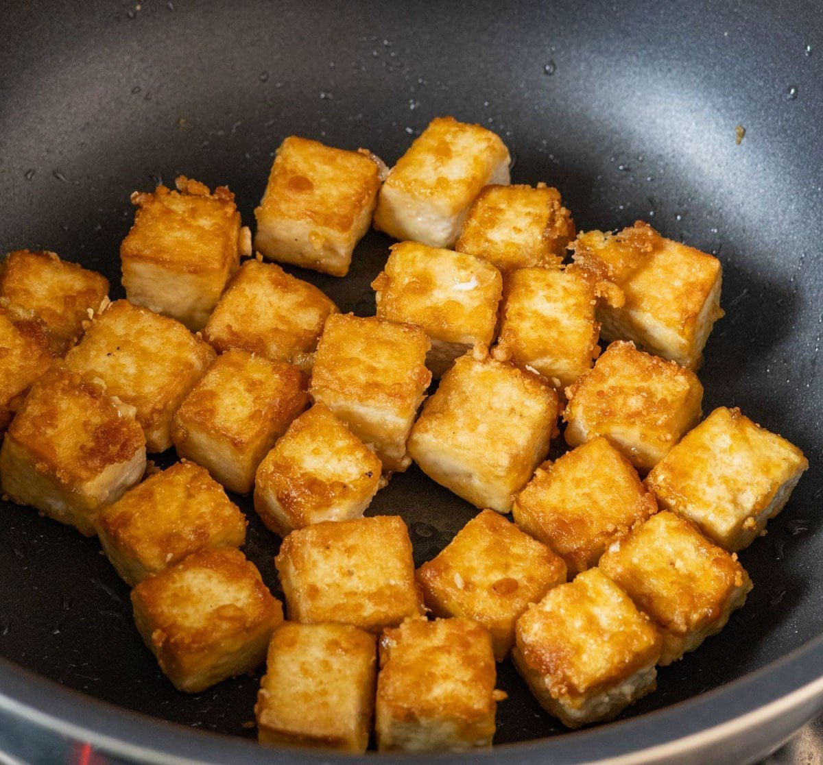 Crispy fried tofu pieces in a black skillet.