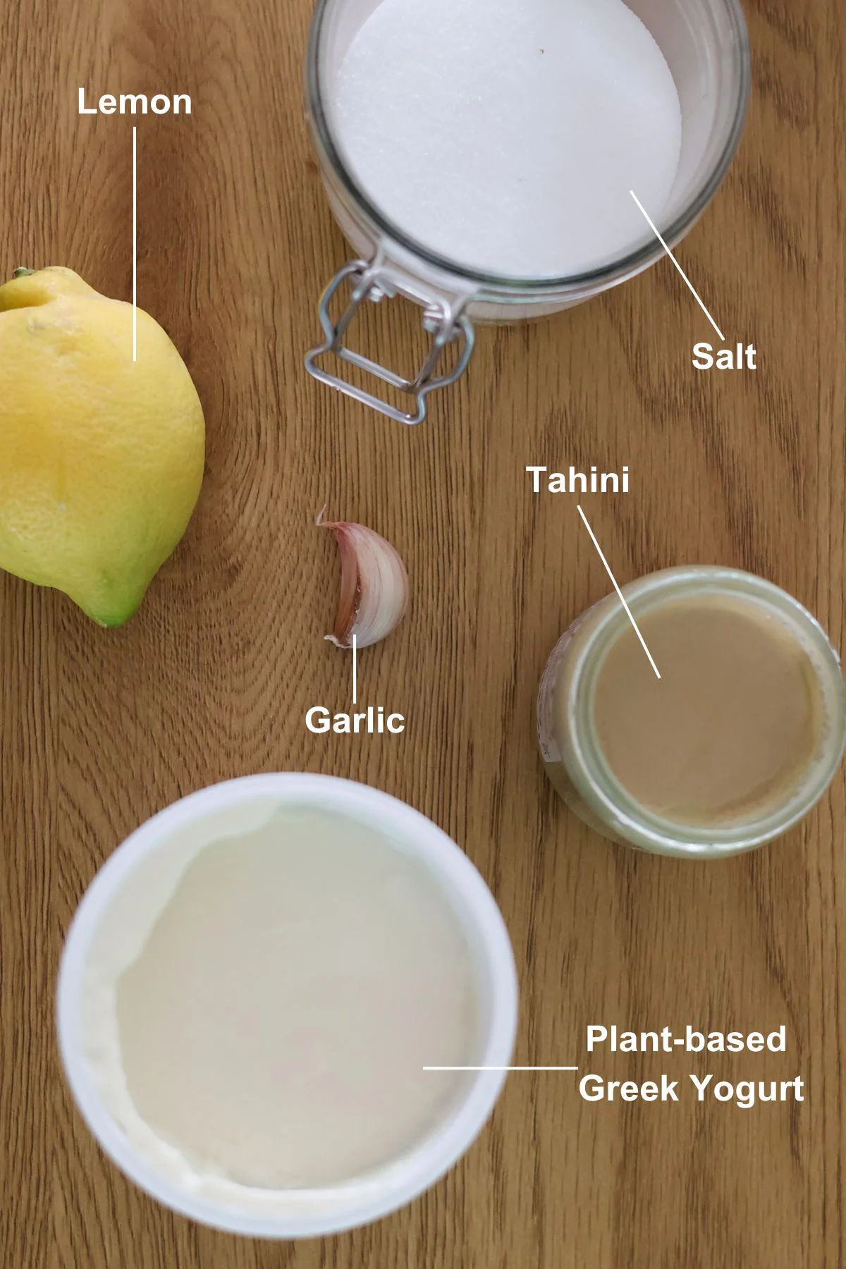 The ingredients for the lemon tahini yogurt sauce recipe on a wooden table.