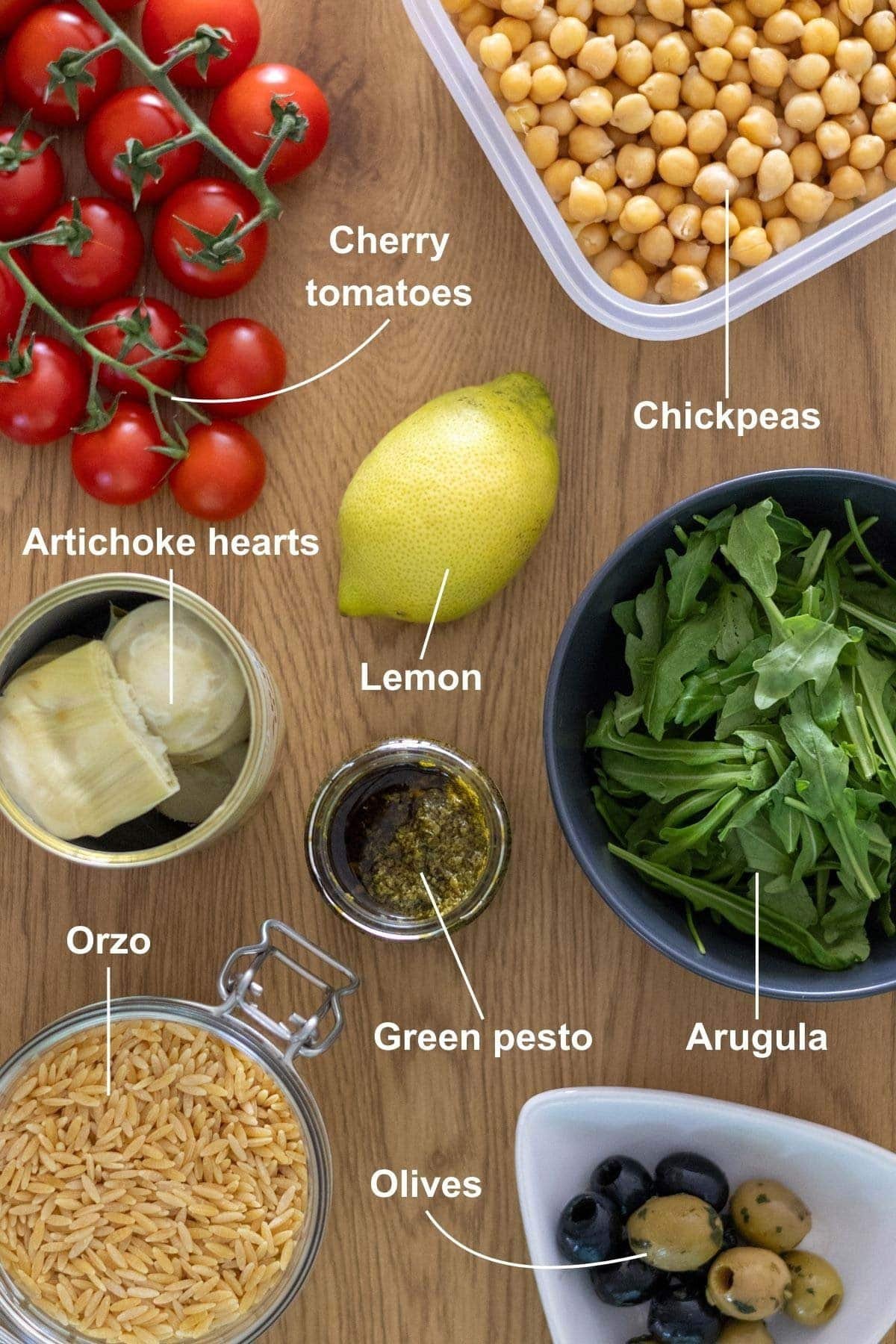 All the ingredients for the vegan orzo salad with pesto on a wooden table.