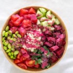 Watermelon, beetroot, cucumber, cherry tomatoes, edamame, pearl couscous, fresh mint and Thai Basil in a wooden bowl served with a beetroot sauce.