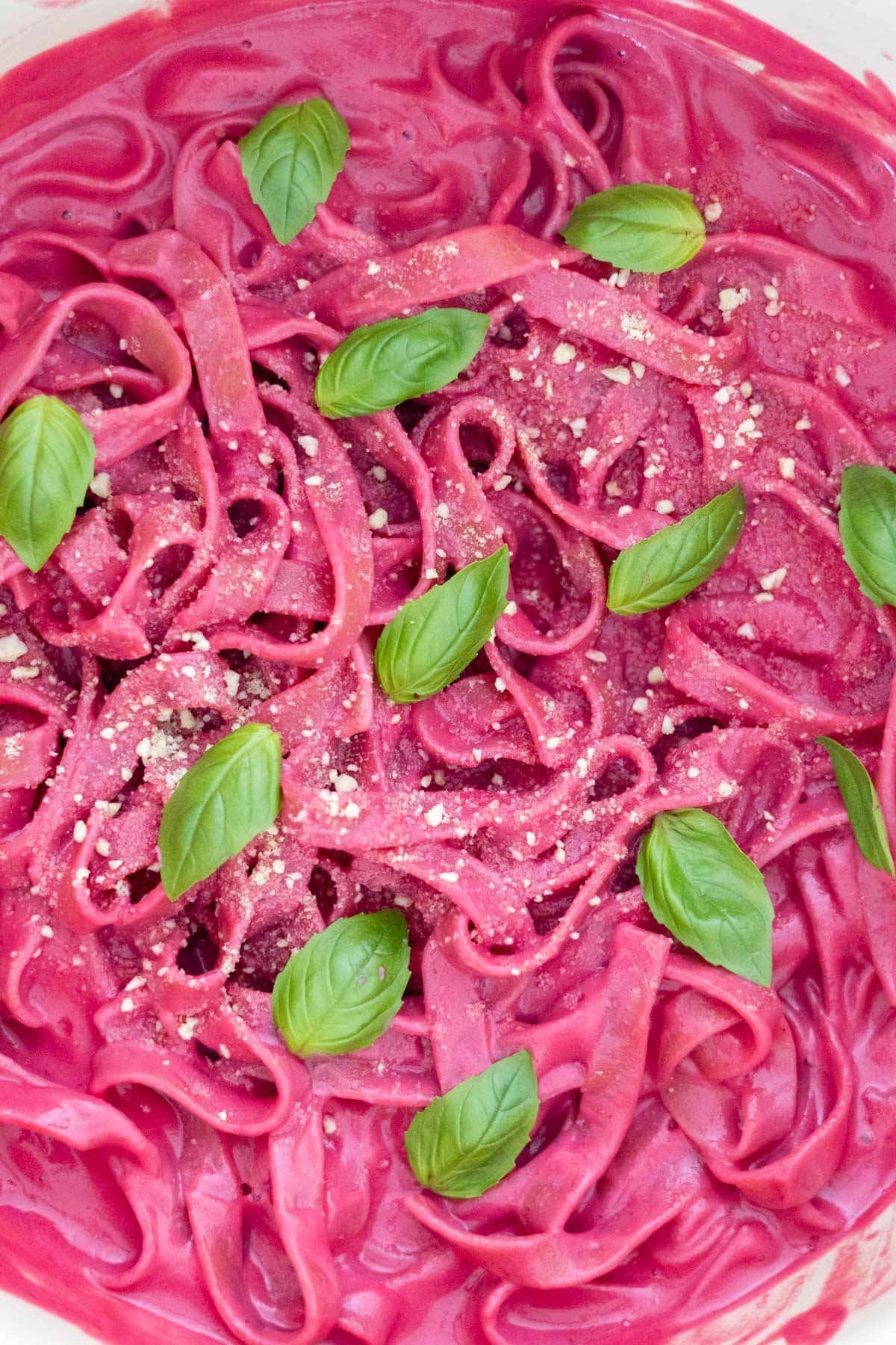 Tagliatelle covered in a beetroot pasta sauce topped with fresh basil and vegan parmesan cheese.