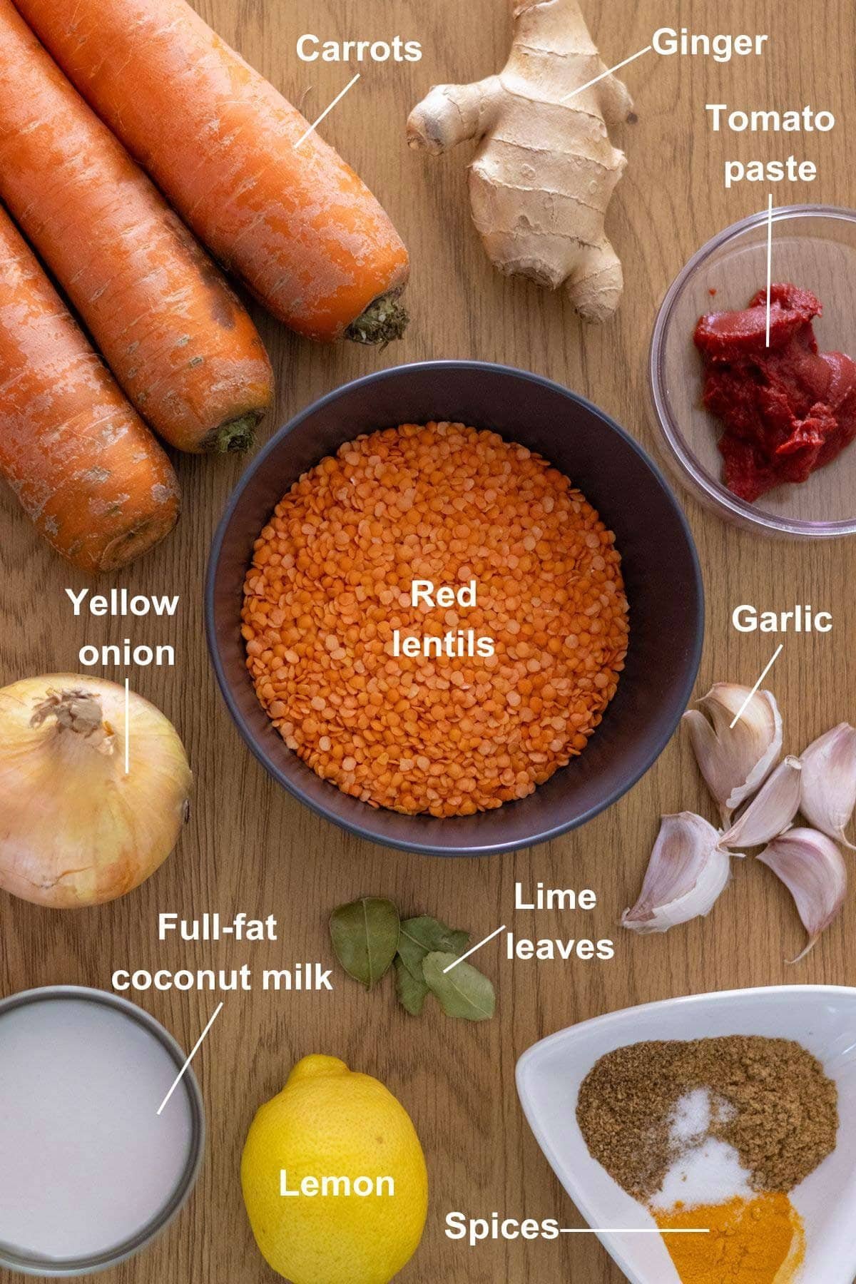 All the ingredients for the carrot and lentil soup on a wooden table.