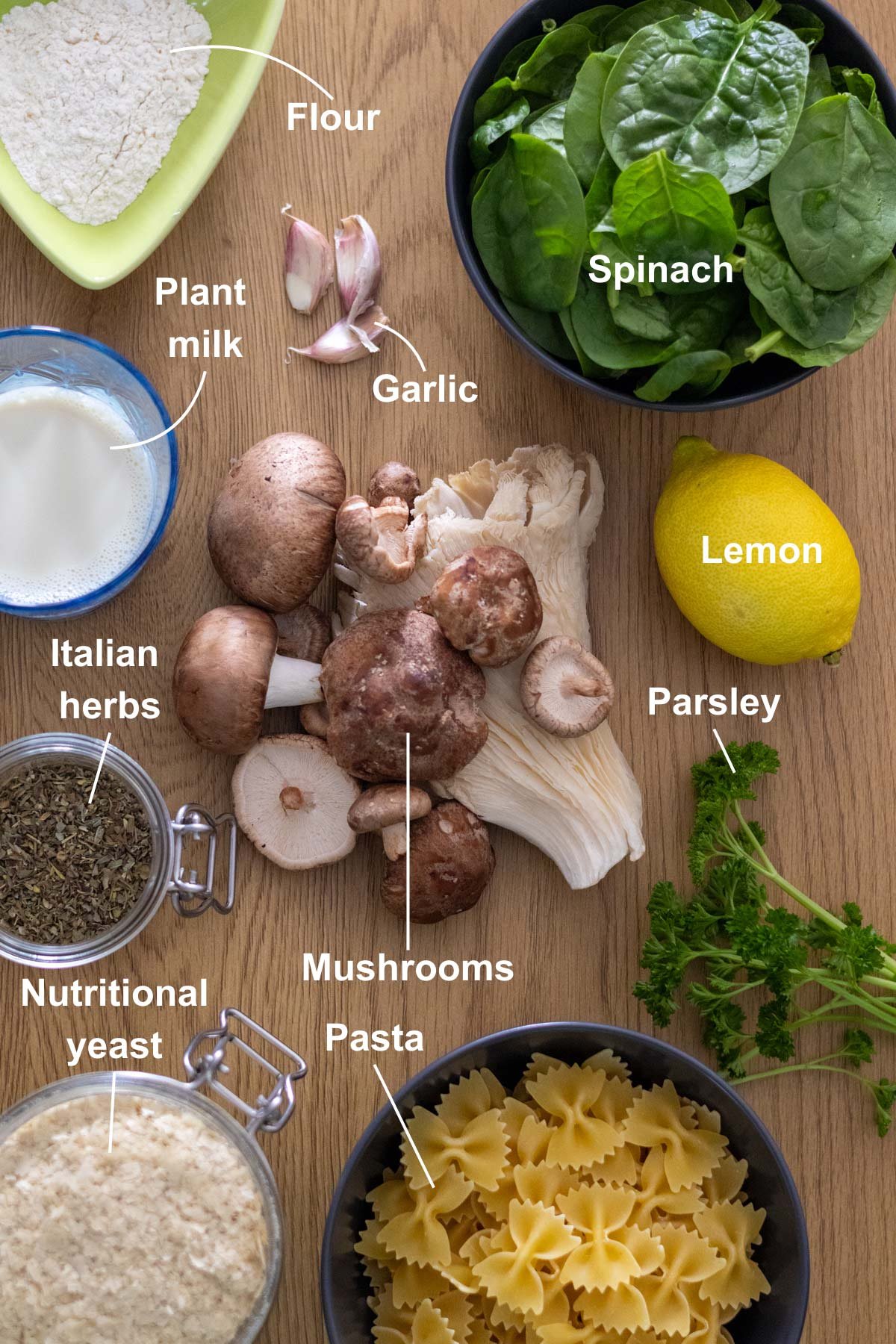 All the ingredients for the Spinach and Mushroom Pasta recipe on a wooden table.